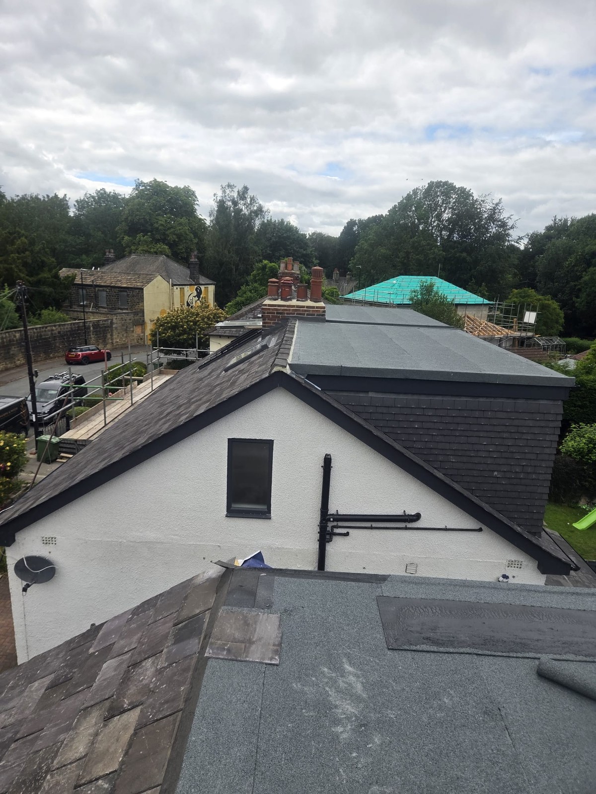 View across flat roof surfaces and a pitched roof with a white rendered gable