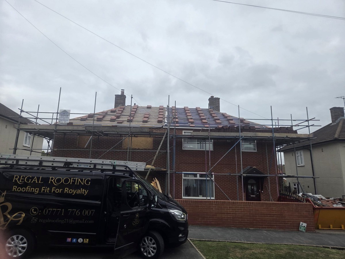 Roof with exposed battens and rows of tiles above scaffolding, with a Regal Roofing van below