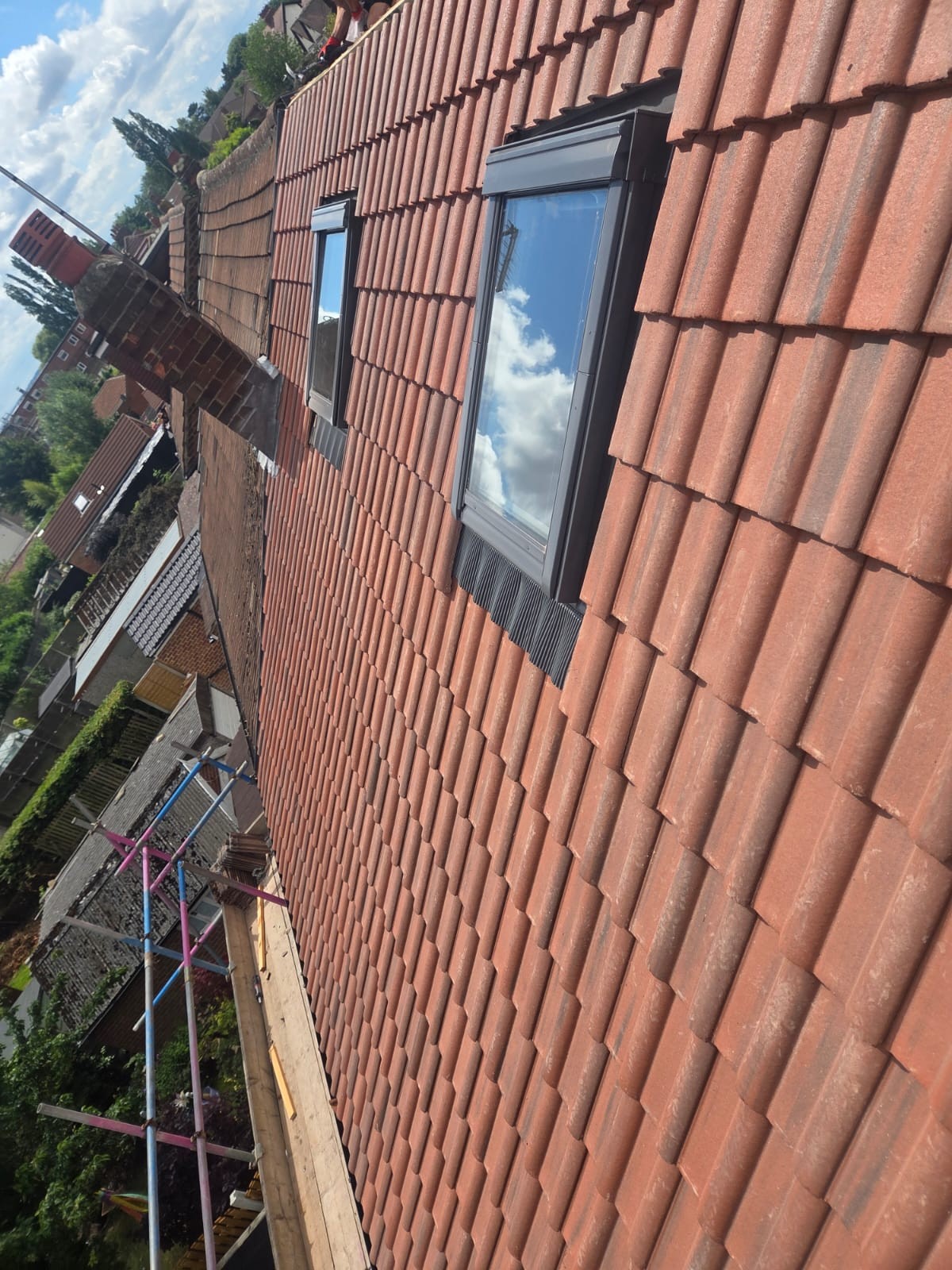Two glazed roof windows set into a red tiled pitched roof beside a brick chimney