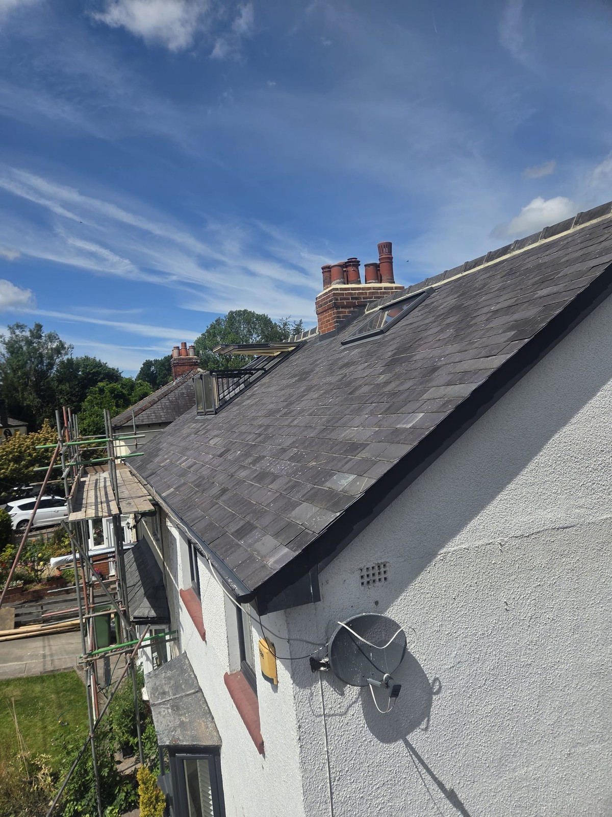 Slate-covered pitched roof with ridge tiles above a white rendered gable